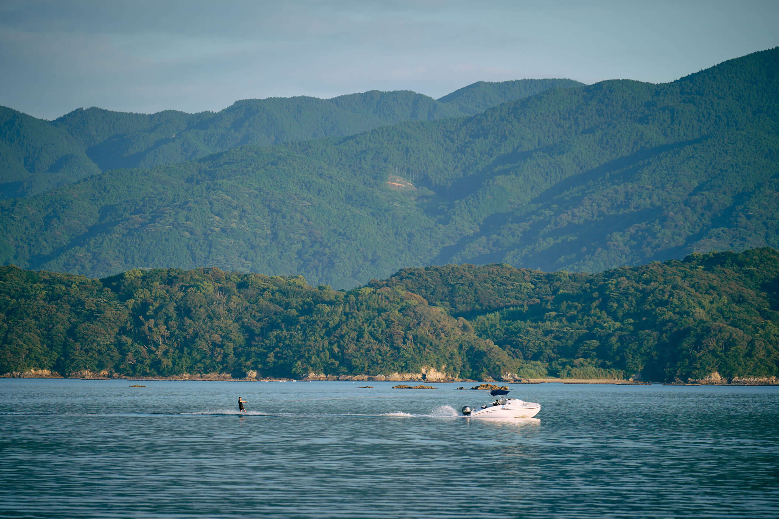 青い海を背景に、ボートに引かれて海上を滑る人物
